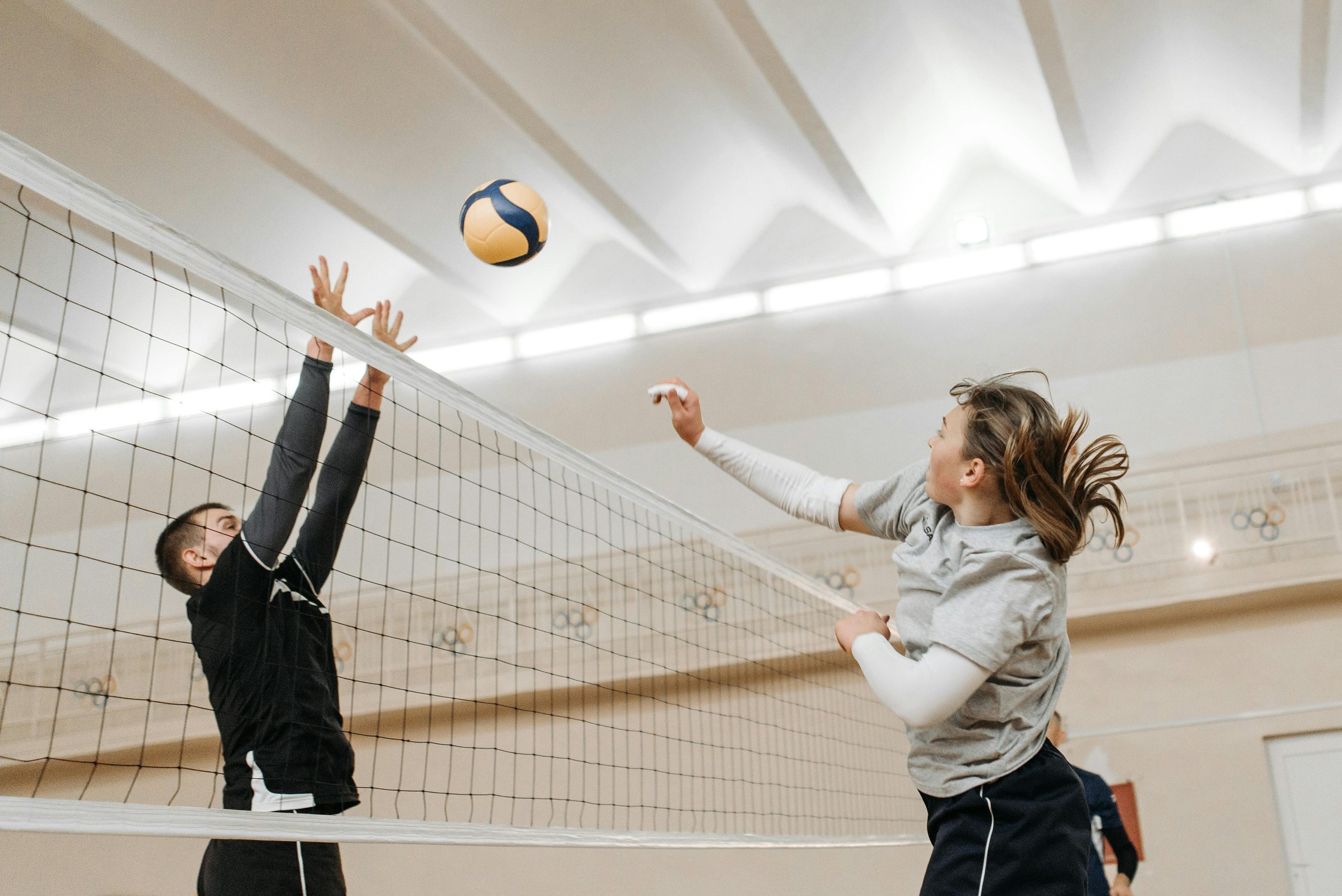 Two athletes engaged in a thrilling volleyball match indoors, showcasing competitive spirit and energy.