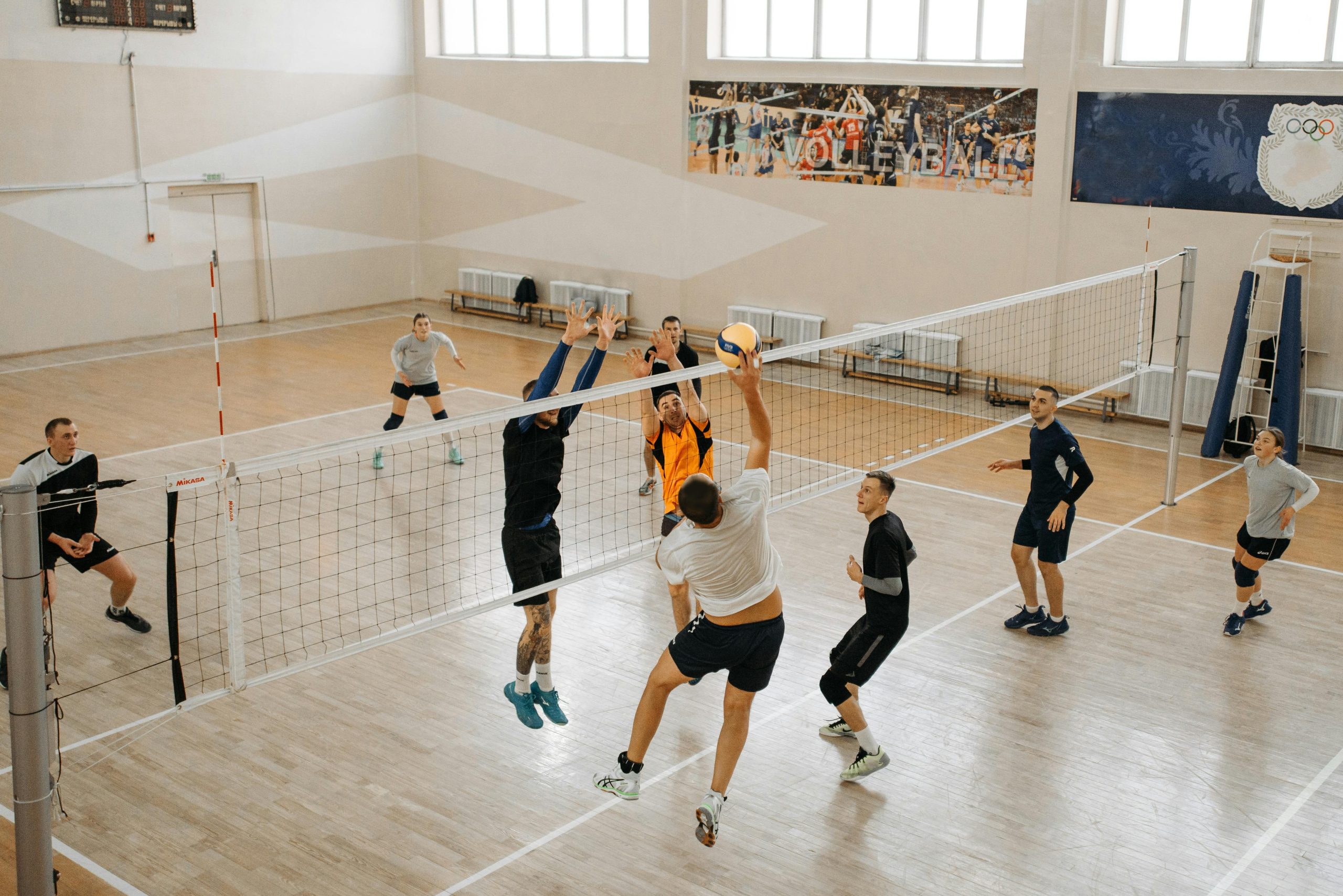 Exciting indoor volleyball game featuring diverse teams in action, jumping and playing.
